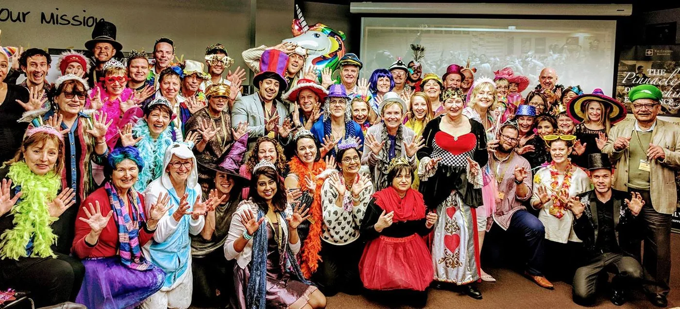Remi with a room of people in fancy dress at a Coaching Institute celebration