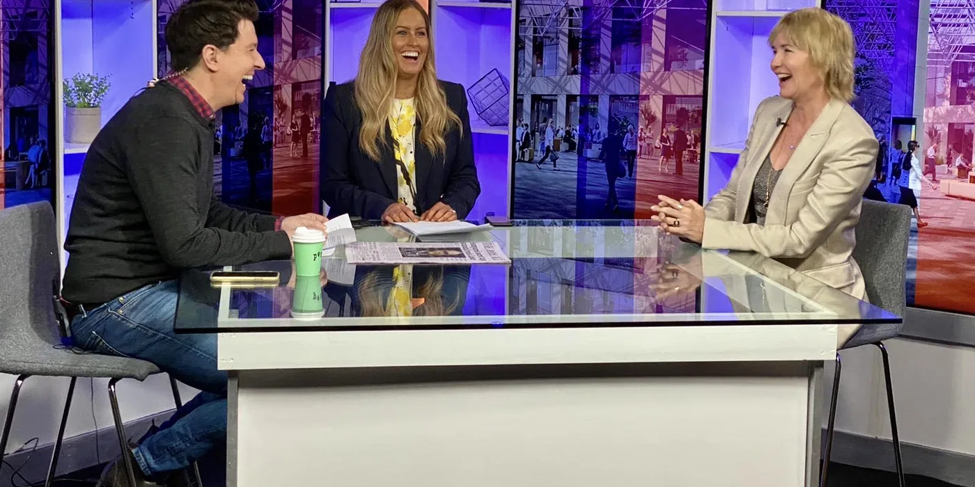 Remi in conversation with two hosts on a television set