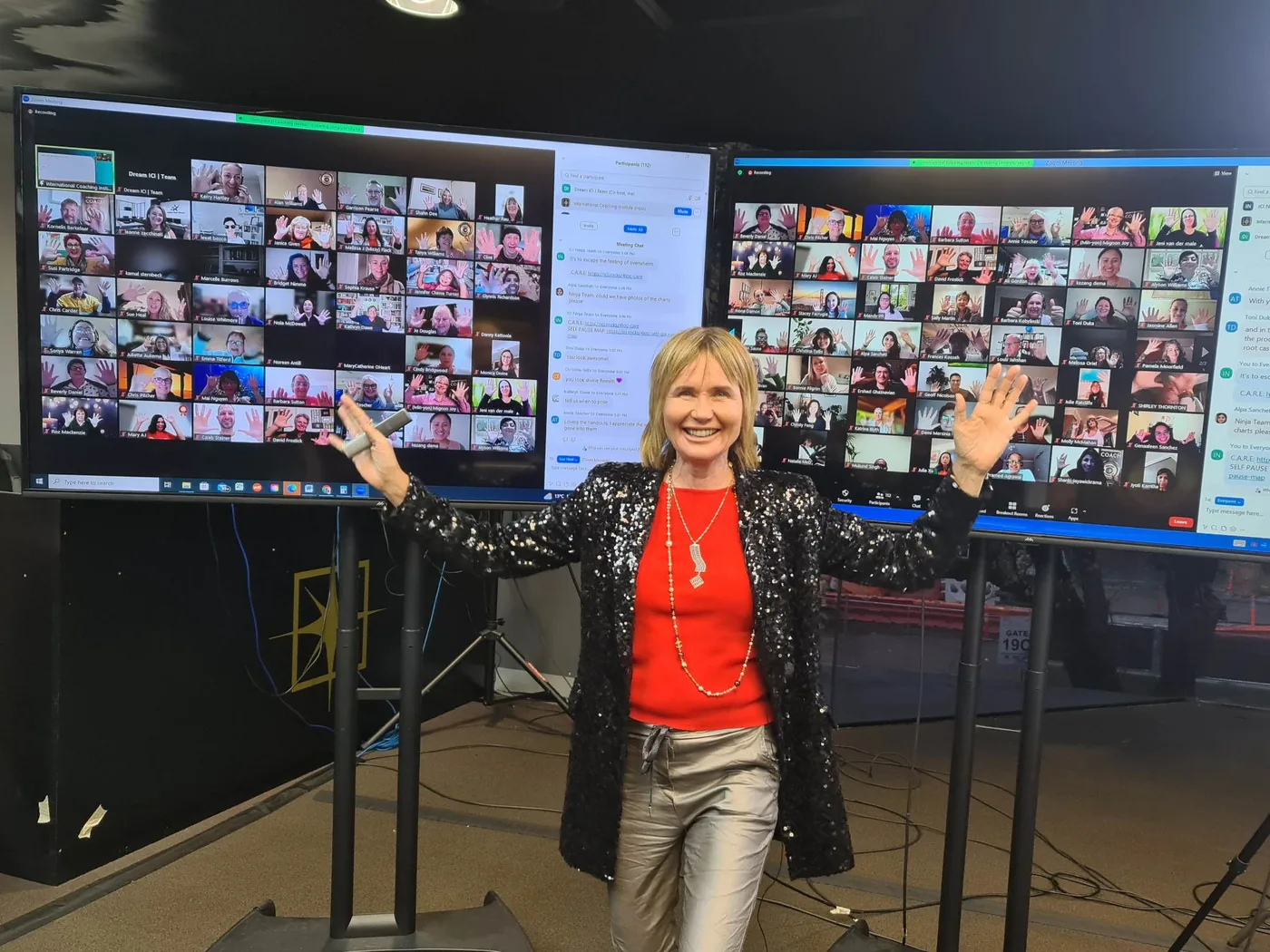 Remi, arms wide, in front of screens full of online attendees