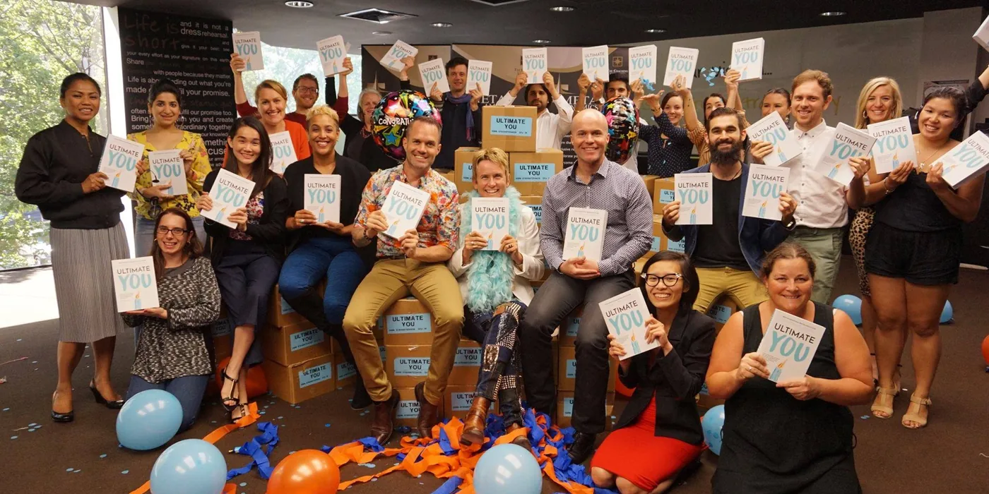 Remi’s team holding up copies of her book among balloons