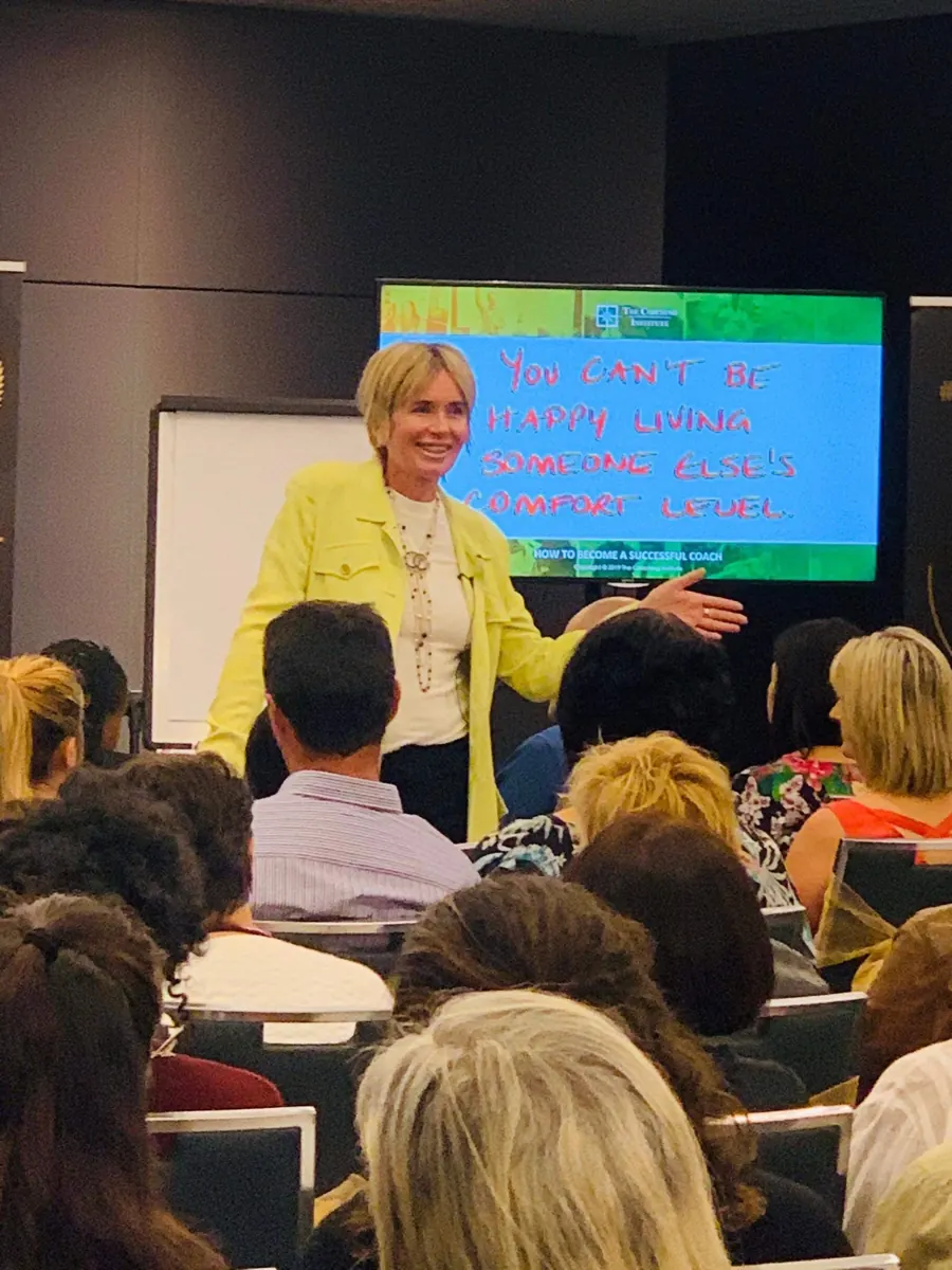 Remi teaching in front of a screen that reads “You can't be happy living someone else's comfort level”